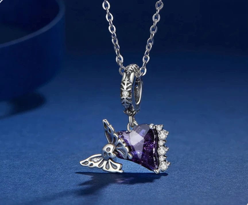 Dije colgante con forma de calavera y mariposa sobre corazón morado